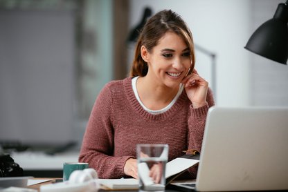 Frau am Schreibtisch mit Laptop bei Online-Rufnummernmitnahme