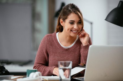 Frau am Schreibtisch mit Laptop bei Online-Rufnummernmitnahme