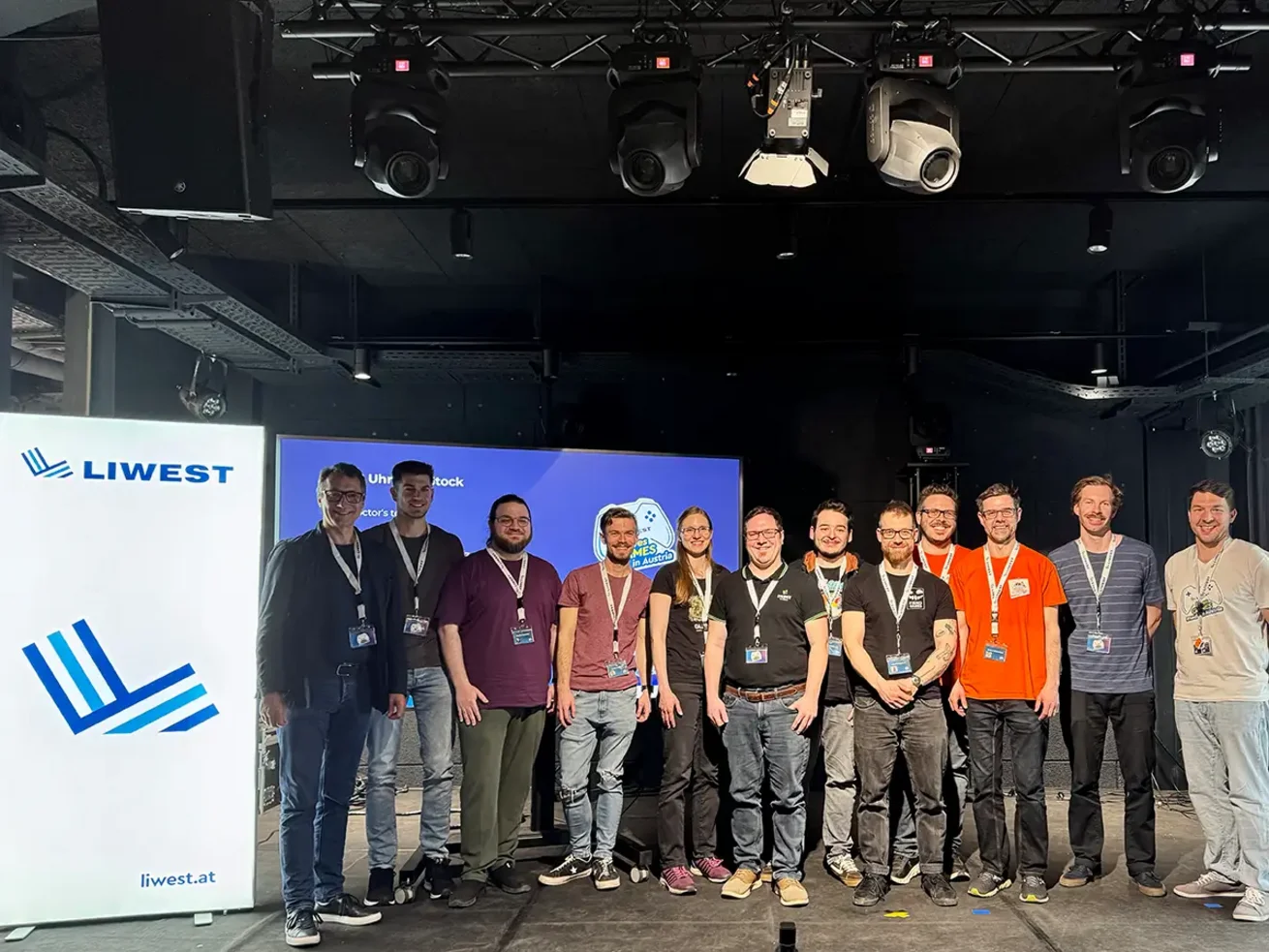 12 Personen auf der Bühne im last by Schachermayer. Die meisten sind Entwickler, die ihre eigenen Videospiele vorgestellt haben. Ganz links steht der Geschäftsführer der LIWEST Kabelmedien GmbH Stefan Gintenreiter.