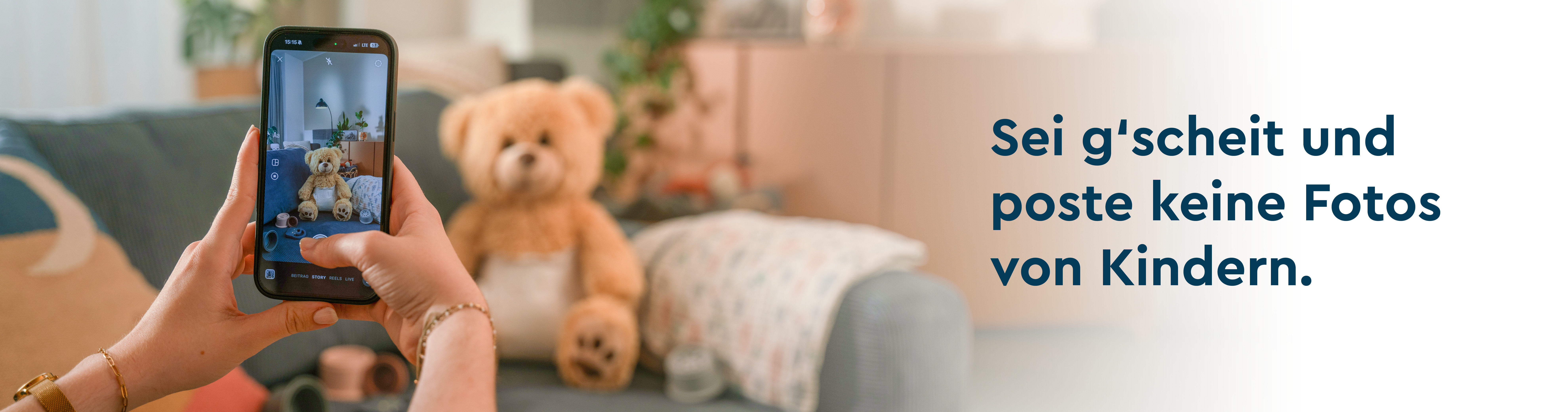 Man sieht zwei Hände die ein Mobiltelefon halten und ein Foto von einem Teddy Bär erstellen.