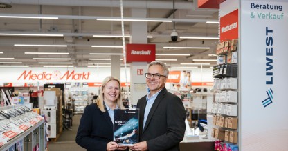 Daniela Zwieb (MediaMarkt) neben Robert Böhm (LIWEST) in Telekom-Abteilung im MediaMarkt Linz Industriezeile mit Schild Gigantisch starkes Internet von LIWEST in den Händen