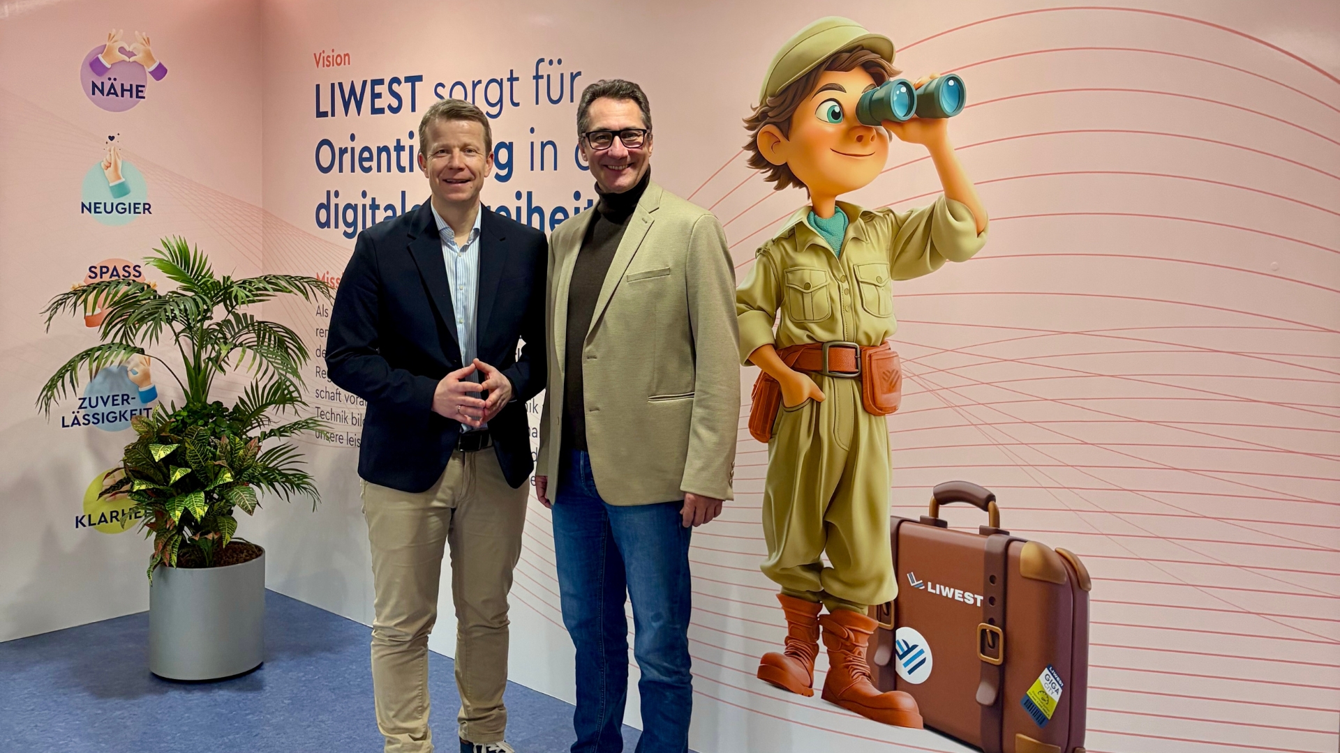 Paul Eiselsberg und Stefan Gintenreiter vor der hellroten Wand mit der LIWEST Vision- und Mission-Statements sowie den Werten