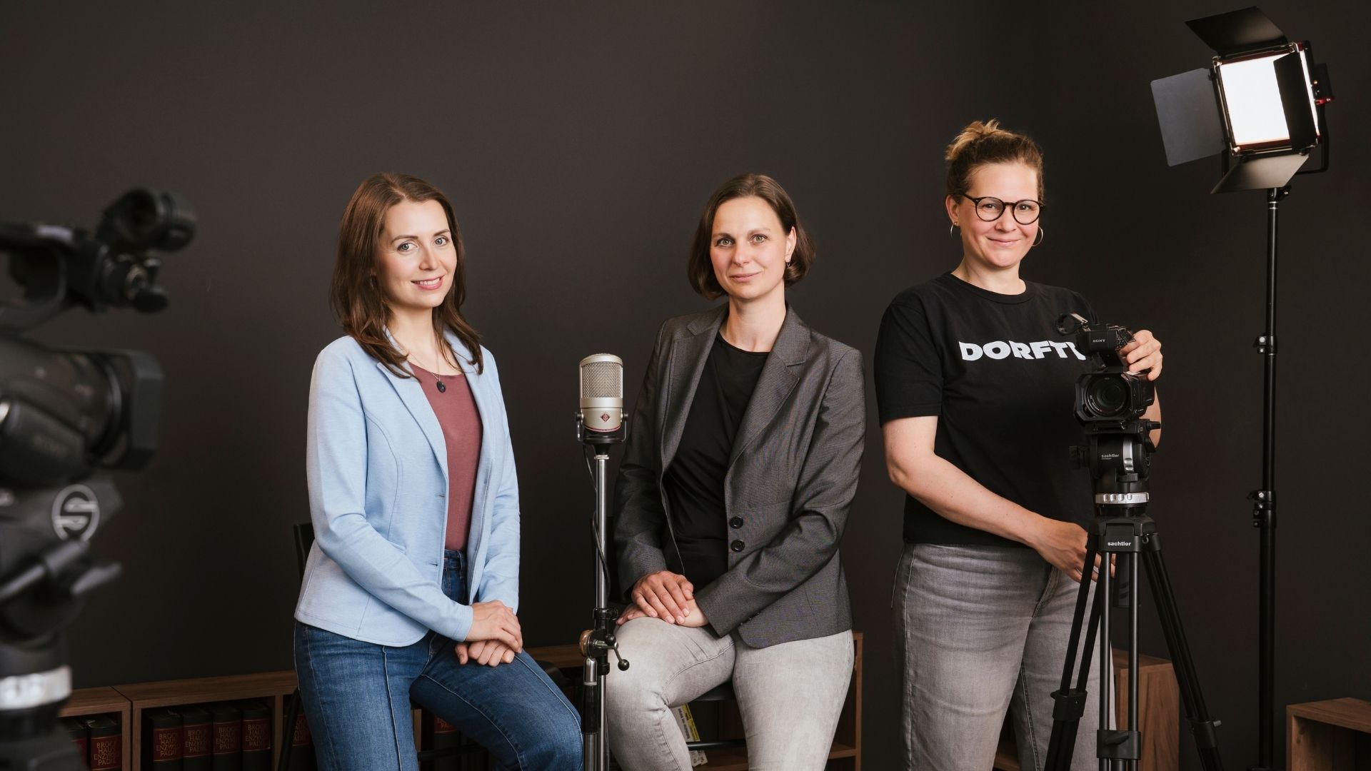 Orliczek, Becker & Nagele im DORFTV Studio mit Kamera, Mikrofon und Scheinwerfer mit schwarzem Hintergrund