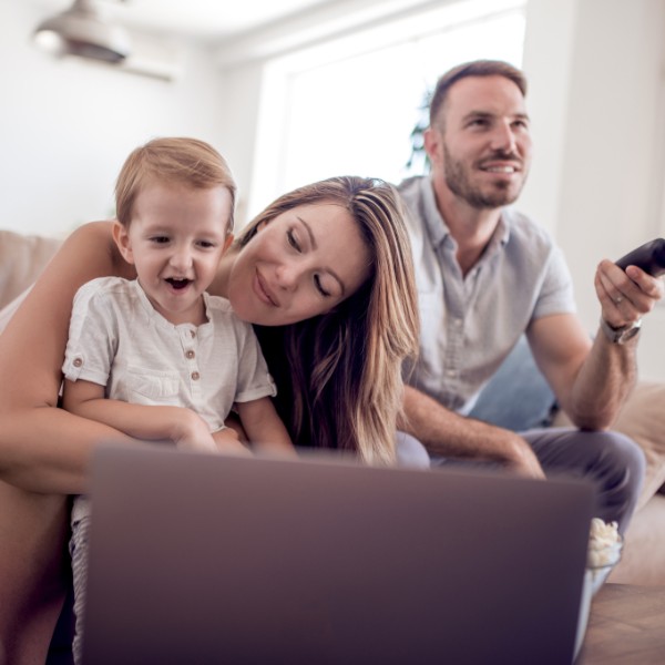 LIWEST Kombi Super 2025 Familie mit Kind, Mutter, Vater und Fernbedienung auf der Couch vor Laptop
