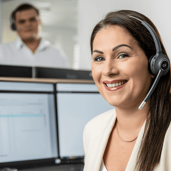 LIWEST Kundendienst Mitarbeiterin lächelnd vor Computerbildschirmen mit Headseat