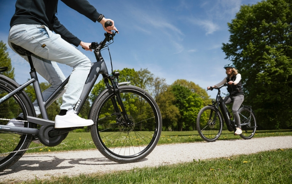 Zwei E-Bikes auf Schotterradweg im Park aufeinander zufahrend
