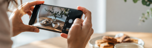 Eine Frau hält ihr Handy in den Händen und fotografiert den gedeckten Tisch.