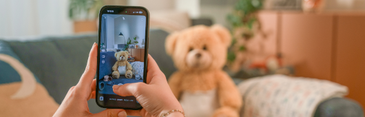 Man sieht Hände, die mit dem Handy die Aufnahme von einem Teddy machen.